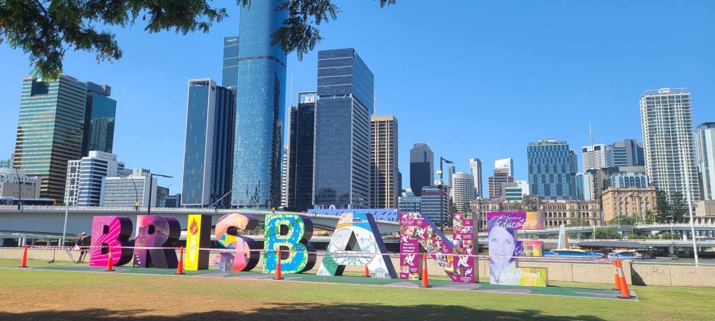 Letters spelling “Brisbane” feature against a city backdrop